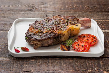 Grilled tomahawk steak on the bone on a ceramic plate