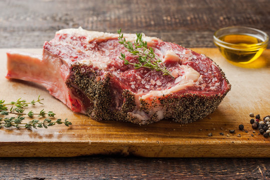 Tomahawk steak on the bone with thyme on cutting board