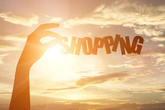 silhouette of a hand holding "shopping" paper text