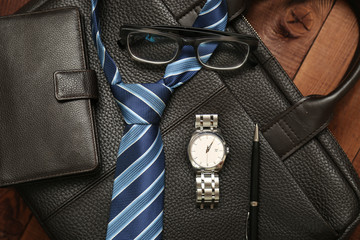 Business man essentials: leather wallet, blue tie, watch and pen.
