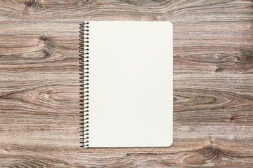 Mockup of open notepad with blank page on wooden background.