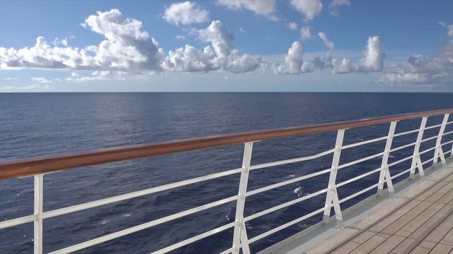 Cruise ship railing, blue sky, tranquil water at sea with horizon