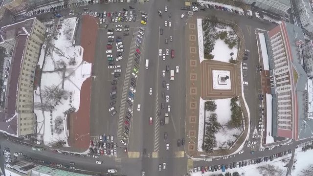 Flying over the Red Square, the city centre of Kursk, Russia. View to the car traffic on the road, buildings and monument on dull winter day