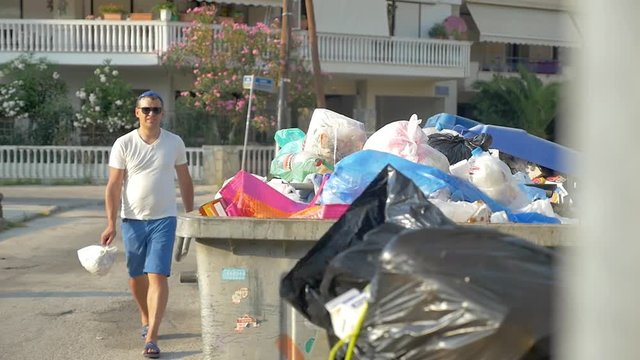 Slow motion shot of a young man throwing trash pack to full container.