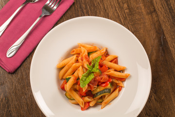 close up of pasta with tomatoes, zucchini and basil