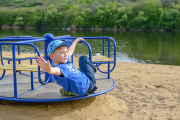 Little boy on a spinning merry-go-round waving