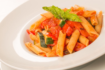close up of pasta with tomatoes, zucchini and basil