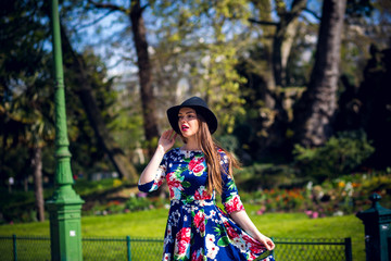 Beautiful fashionable woman in a hat and dress staging