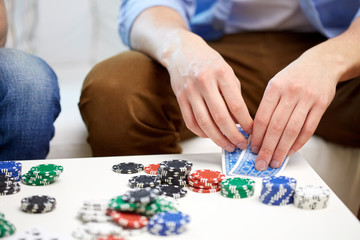 close up of male hand with playing cards and chips
