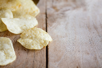 Opened pack of delicious potato chips on wood table