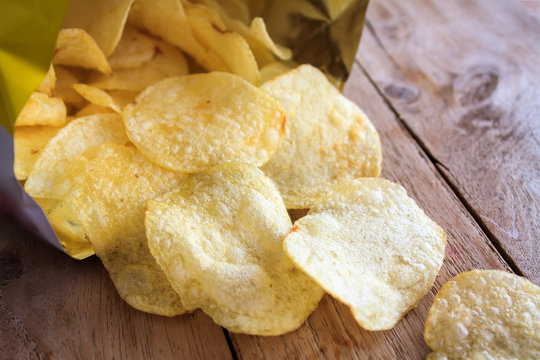 Opened Pack Of Delicious Potato Chips On Wood Table