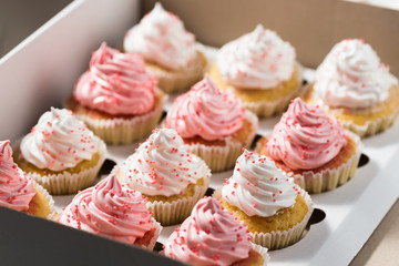 Cupcake packaging, delivery box, vanilla cupcakes with pink and white cream, selective focus, close...