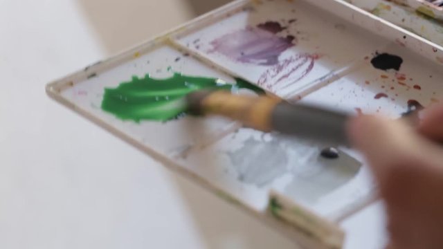 Girl draws abstraction in watercolor on white paper. Filmed using rig.