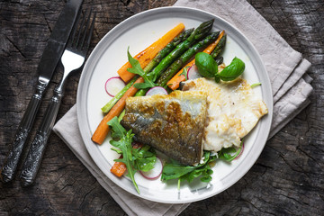 Fish fillet with vegetables on wooden background