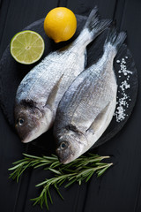 Stone slate with two fresh uncooked dorados, high angle view