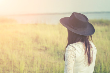 sad woman wearing black hat standing in a meadow