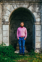 Fototapeta na wymiar A young man with a beard standing against the background of the old castle and smiling