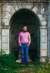 Fototapeta na wymiar A young man with a beard standing against the background of the old castle and smiling