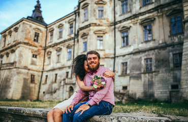 Fototapeta na wymiar Beautiful couple, posing in near olf castle. Man with beard, woman with curly hair