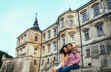 Beautiful couple, posing in near olf castle. Man with beard, woman with curly hair