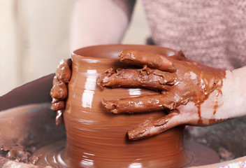 Close-up of potter's hands with the product on a potter's wheel
