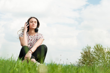 Enjoying music concept with young female sitting outside with ea