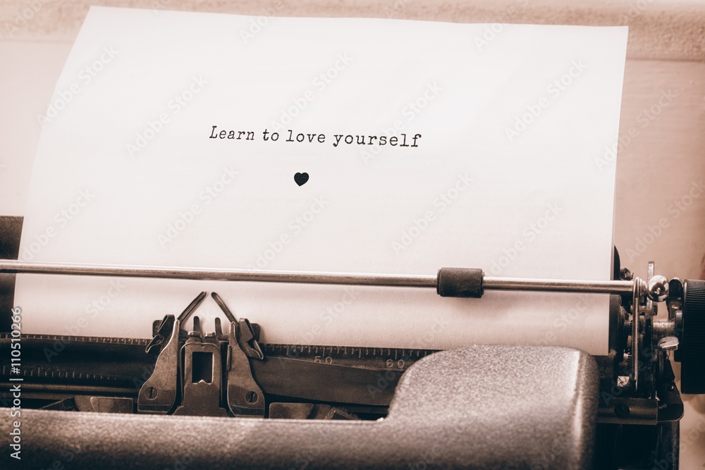Poster learn to love yourself message on a white background against close-up of typewriter