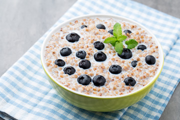 Buckwheat porridge in a bowl with mint leaves and blueberries.