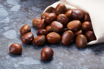 Horizontal image of a pile of chestnuts on stone texture floor with copy space