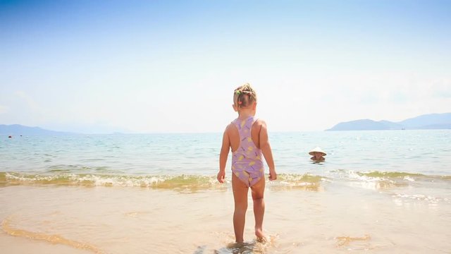 Little Girl Runs across Sea Wave to Mom in Straw Hat