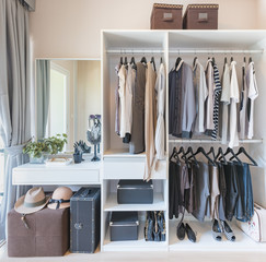 white wardobe and dressing table with clothes hanging