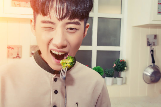 Handsome Young Man Eating Broccoli In The Kitchen Smiley With Cl