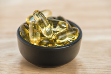 Cod liver oil omega 3 gel capsules in bowl on floor wood