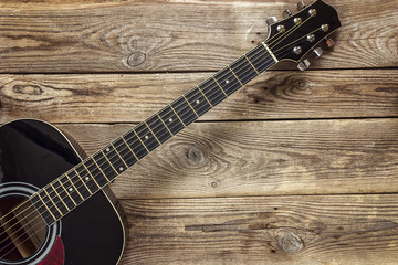 Fototapeta premium Details of black guitar on the background of old grunge boards.