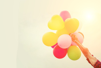 Young woman hands holding balloons against  sky