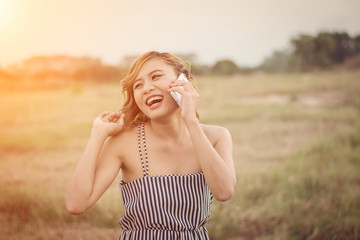 Naklejka premium Beautiful sexy woman standing talking on phone in the grass fiel