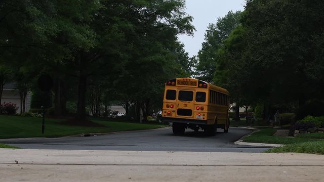 Wide shot of a yellow school bus turning a corner in a neighborhood
