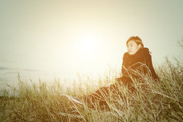 Sad young woman sitting on the grass feeling so sad and loneline
