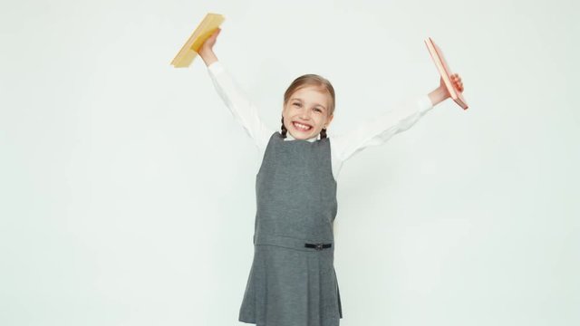 Studying is over. Happy schoolgirl 7-8 years holding books and jumping with books on white background and smiling