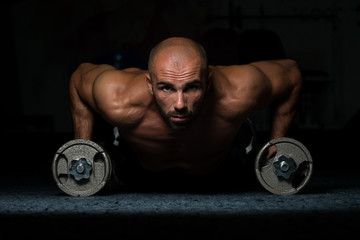 Young Man Exercising Push Ups With Dumbbells