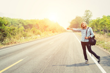 Obraz premium young hipster woman hitchhiking on countryside road wait for the