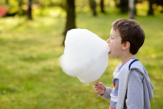  7 years boy eating candy floss in the park