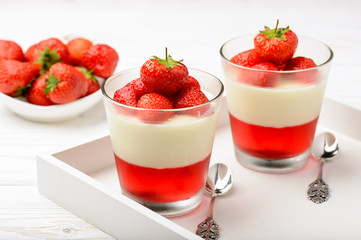 Layered strawberry dessert - panna cotta with strawberry jelly and strawberries.