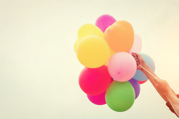 Fototapeta na wymiar Hand of a teenage girl holding colorful balloons in the sunshine