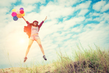 Beautiful Girl jumping with balloons on the beach