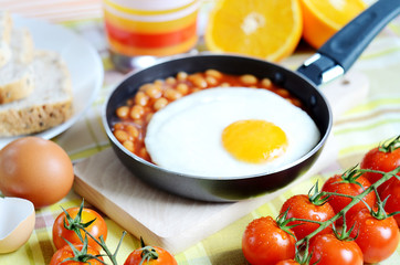 Fried egg with beans, toast bread, fresh juice, tomatoes and oranges