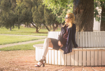 Young adult girl sitting outdoors sunlight.