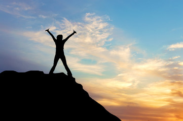 Silhouette of a happy man on the top of a mountain at sunset