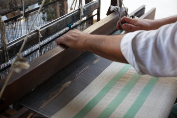 Hand of a man weaving traditional silk fabric