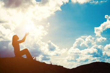 Silhouette of woman praying over beautiful sunrise background